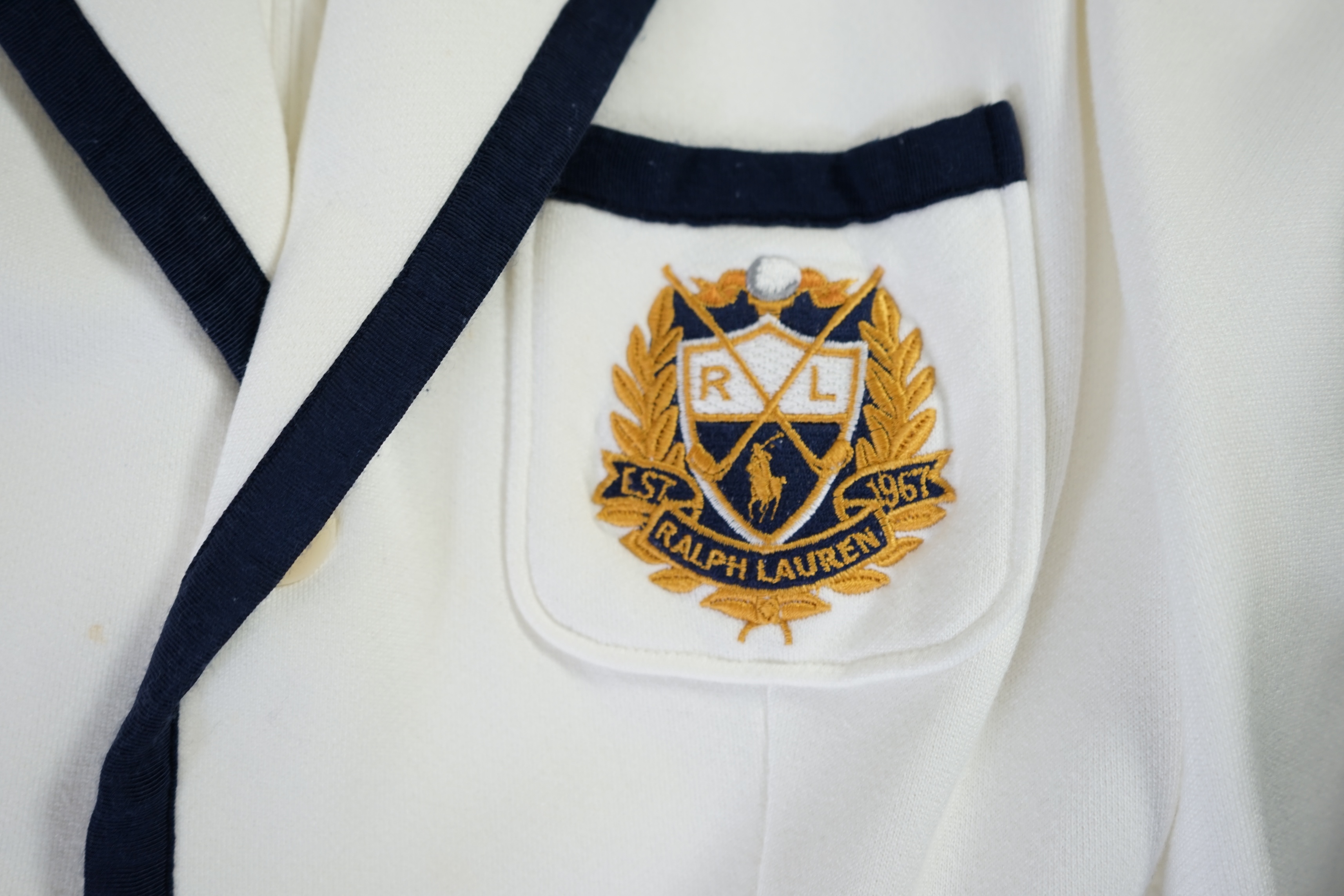 A cream Ralph Lauren blazer with navy blue cord piping. Proceeds to Happy Paws Puppy Rescue